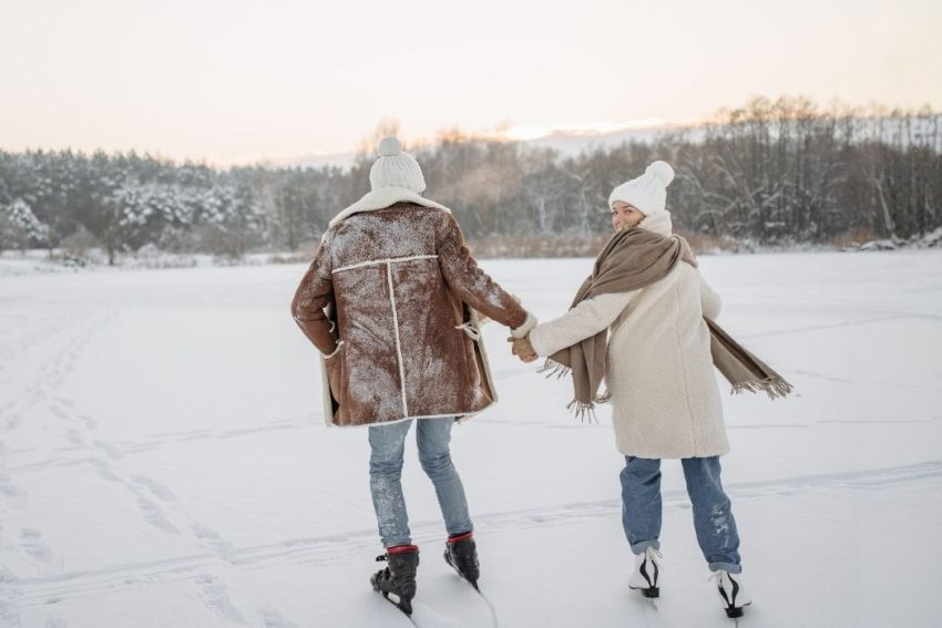Couple ice skating on frozen White Oak Pond near Squam Lake during a New Hampshire winter vacation