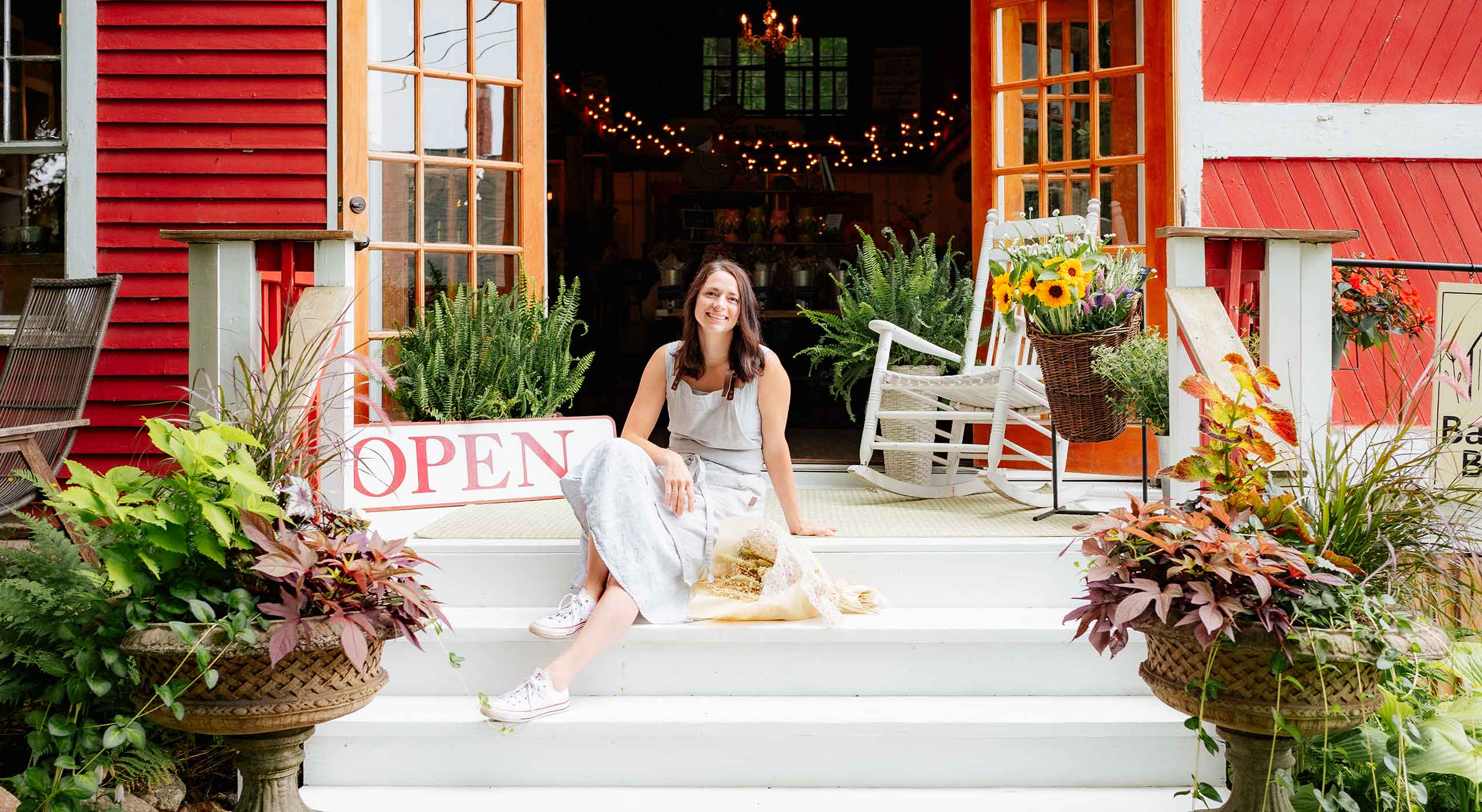 Woman sitting in doorway with bouquet of flowers at Barn INN Bloom gift & flower shop